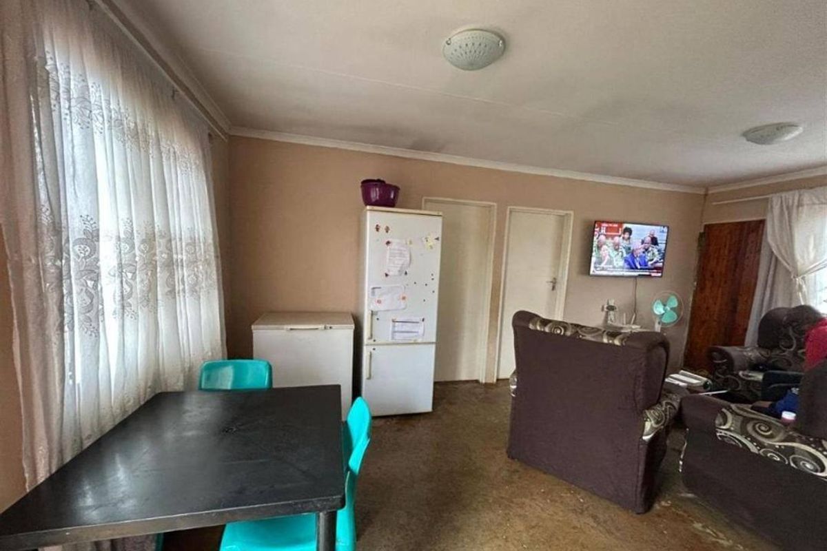 Open plan living and dining area featuring neutral wall tones and large windows with curtain treatments.