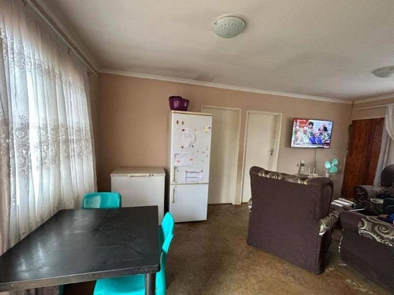 Open plan living and dining area featuring neutral wall tones and large windows with curtain treatments.