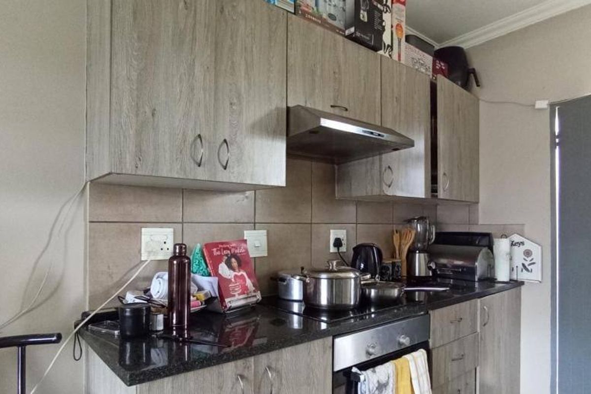 A functional kitchen featuring wood-look laminate cabinetry, granite countertops, a built-in oven, and a tiled backsplash.