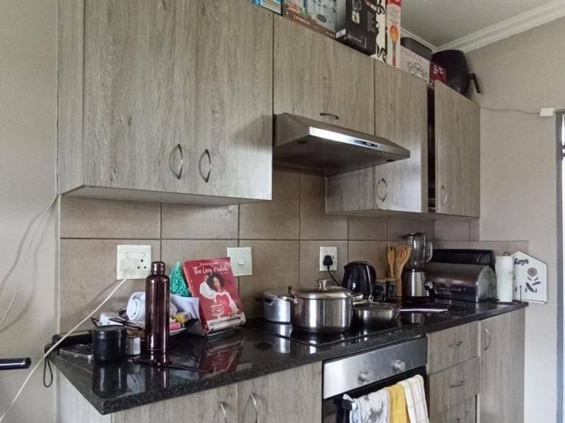 A functional kitchen featuring wood-look laminate cabinetry, granite countertops, a built-in oven, and a tiled backsplash.