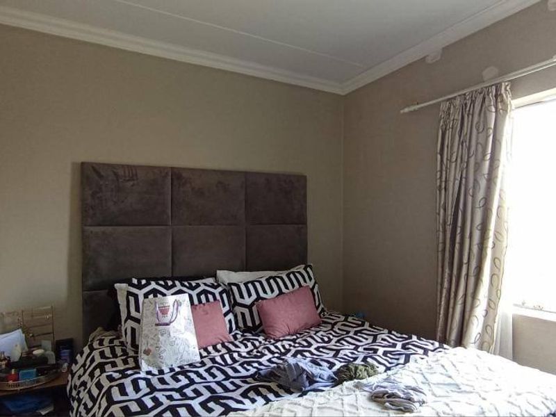 A functional bedroom featuring neutral wall finishes, coving, and a large window with an installed curtain rail.