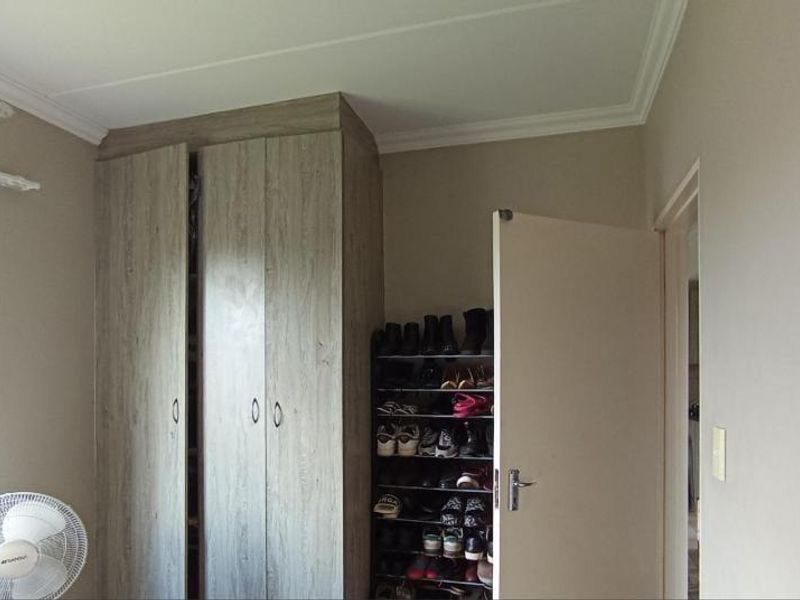 A bedroom featuring built-in wooden cupboards and neutral wall finishes, providing functional storage space within the apartment.