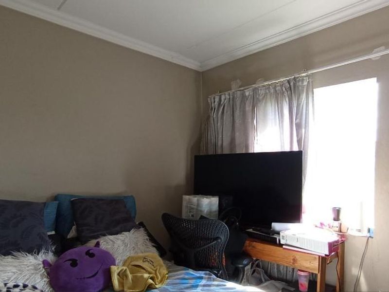A bedroom featuring a window with a curtain rod and crown molding, showing signs of wear on the ceiling and walls.