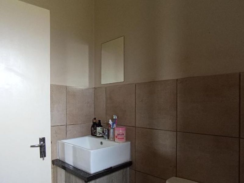 A functional bathroom featuring a modern vessel sink set on a granite-topped vanity cabinet with neutral ceramic wall tiling.