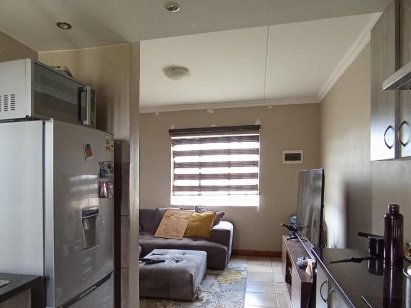 Open-plan kitchen and living area featuring granite countertops, built-in cabinetry, and tiled flooring, offering a functional layout for modern apartment living.