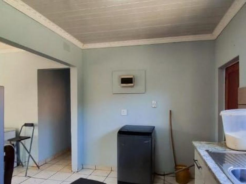 Kitchen area featuring tiled flooring, built-in cabinetry, and a stainless steel sink, offering a functional space with potential for cosmetic updates.