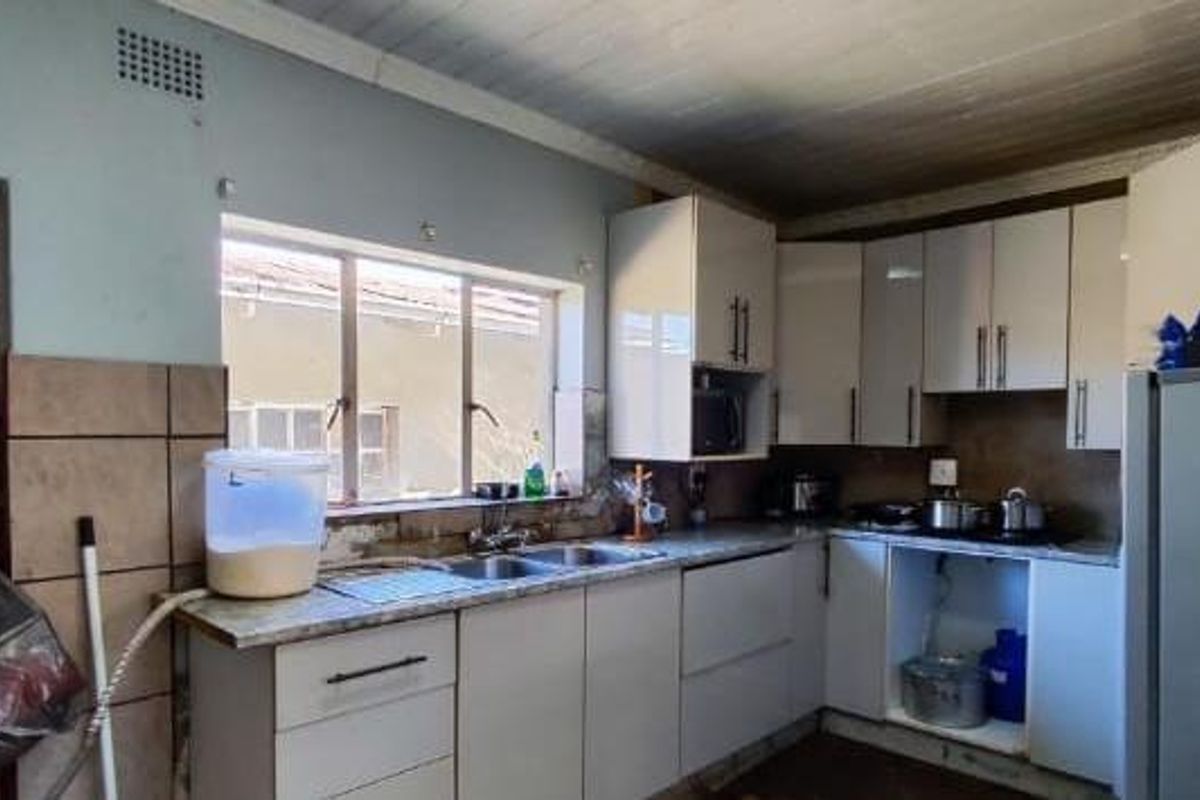 A functional kitchen featuring built-in cabinetry, a double basin sink, and tiled splashbacks, offering potential for cosmetic updates and modernization.