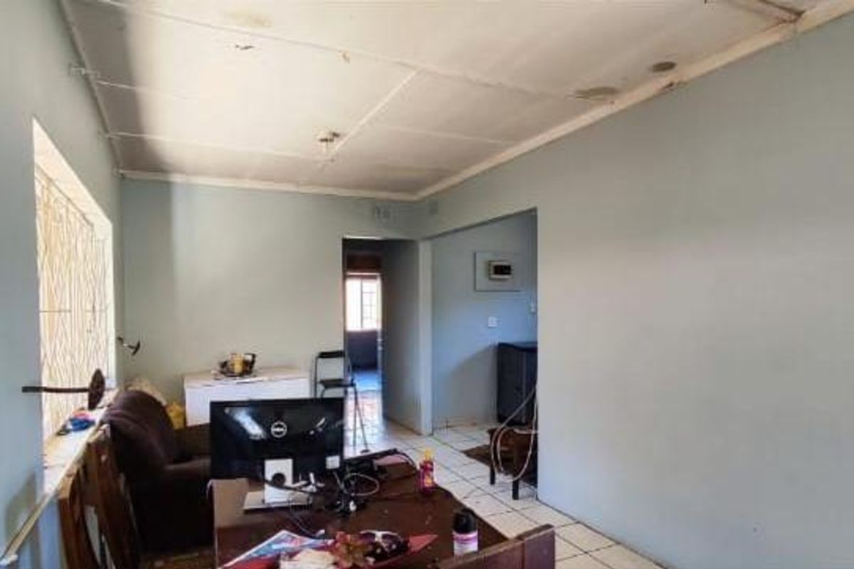 A living area featuring tiled flooring and security bars on the windows, with visible signs of wear on the ceiling panels.