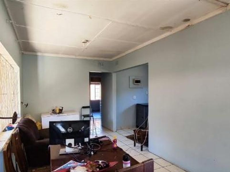 A living area featuring tiled flooring and security bars on the windows, with visible signs of wear on the ceiling panels.