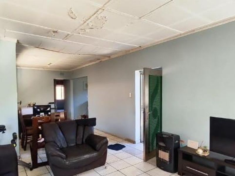 Open plan living area featuring tiled flooring and a ceiling requiring maintenance and repair.