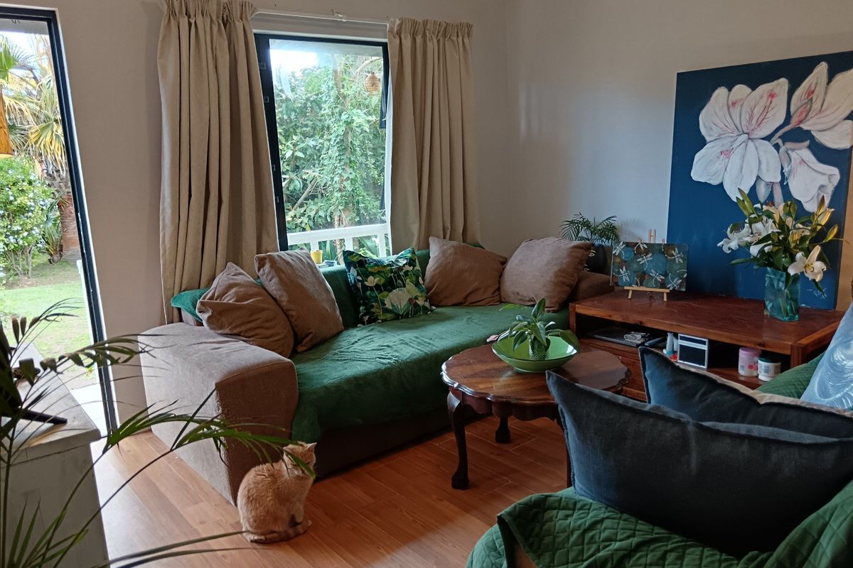 A comfortable living room featuring laminate flooring and a large sliding glass door that provides natural light and access to the garden.