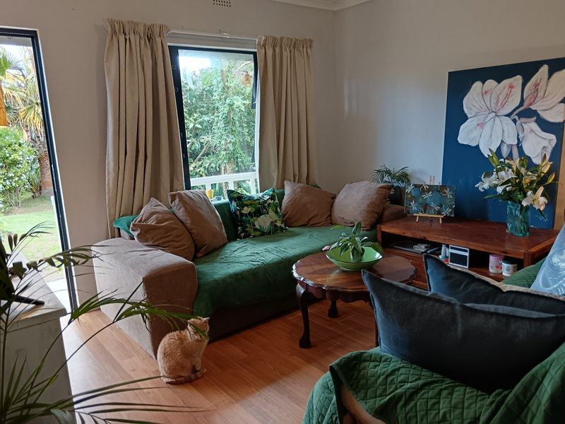 A comfortable living room featuring laminate flooring and a large sliding glass door that provides natural light and access to the garden.