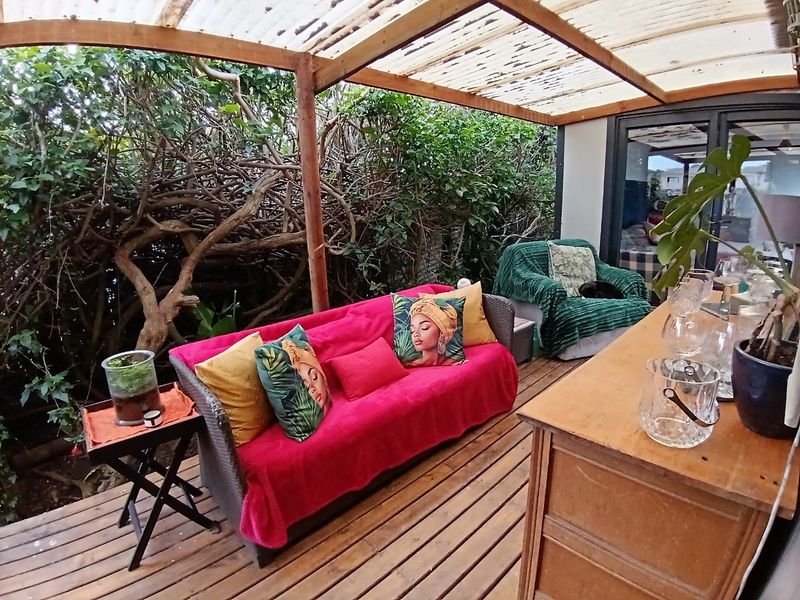 A covered outdoor patio area featuring timber decking and a translucent roof, providing a sheltered space for relaxation adjacent to the main living area.