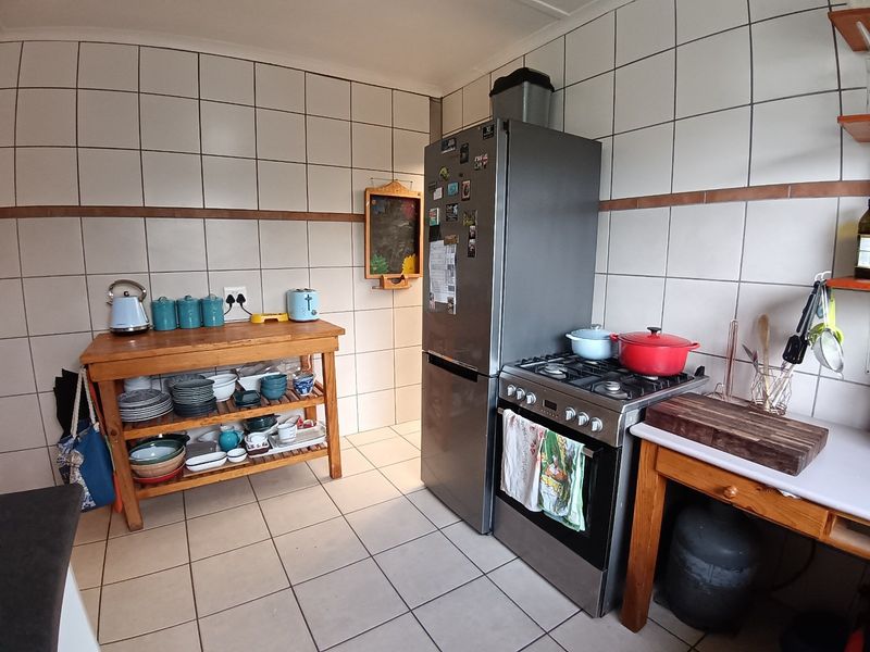 A functional kitchen area featuring tiled walls, tiled flooring, and a freestanding gas stove with oven.
