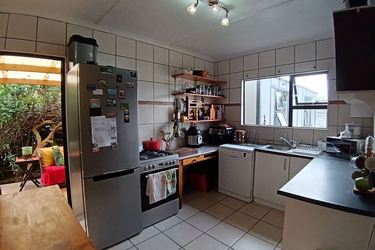 Functional kitchen featuring tiled walls and flooring, built-in cabinetry, a gas stove, and direct access to an outdoor patio area.
