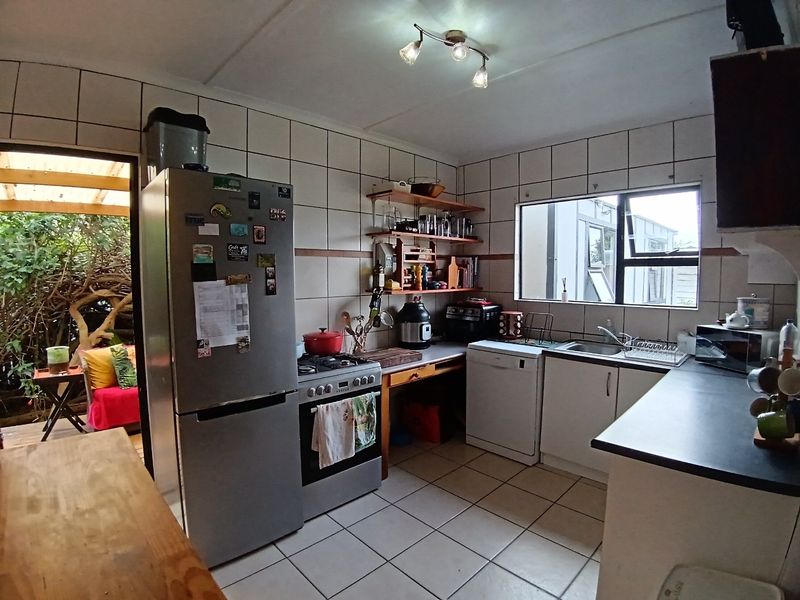 Functional kitchen featuring tiled walls and flooring, built-in cabinetry, a gas stove, and direct access to an outdoor patio area.
