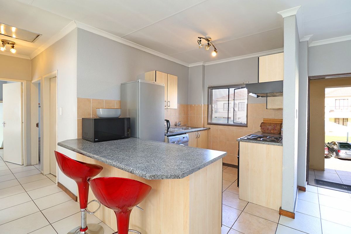 Functional kitchen featuring built-in cabinetry, a breakfast bar, tiled backsplash, and tiled flooring, offering a practical layout for daily meal preparation.