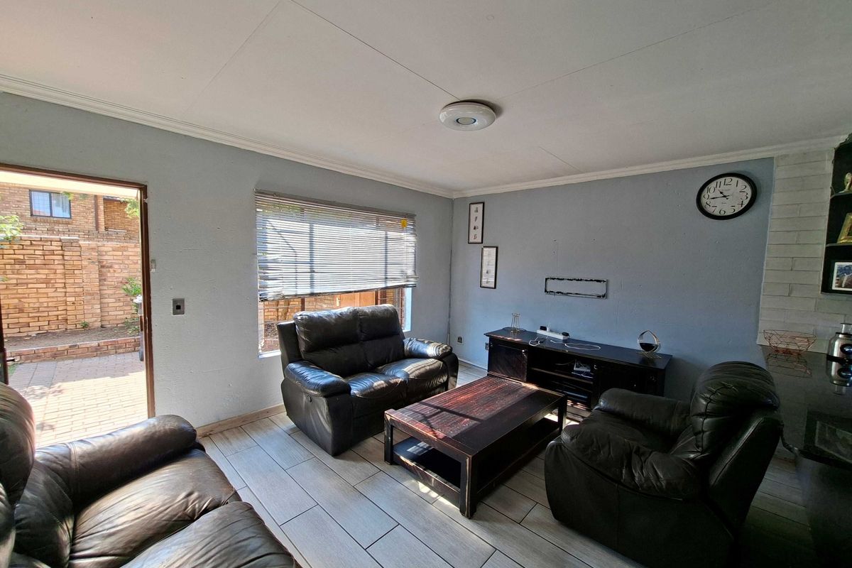 A living room featuring tiled flooring, a brick fireplace surround, and direct access to an outdoor patio area.