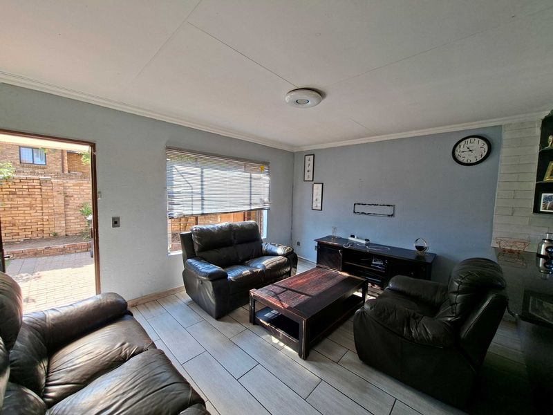 A living room featuring tiled flooring, a brick fireplace surround, and direct access to an outdoor patio area.