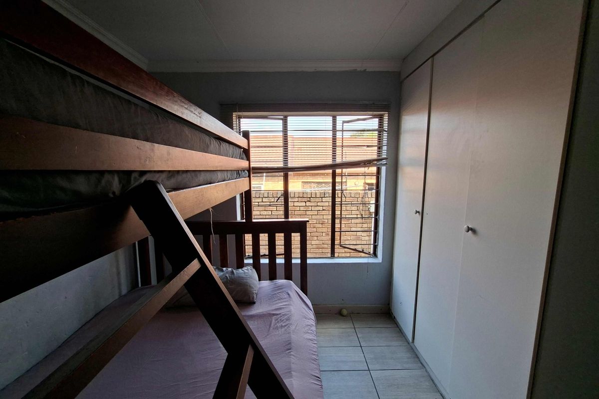 A bedroom featuring tiled flooring and built-in cupboards, providing functional storage space.