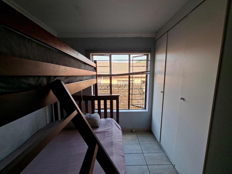 A bedroom featuring tiled flooring and built-in cupboards, providing functional storage space.