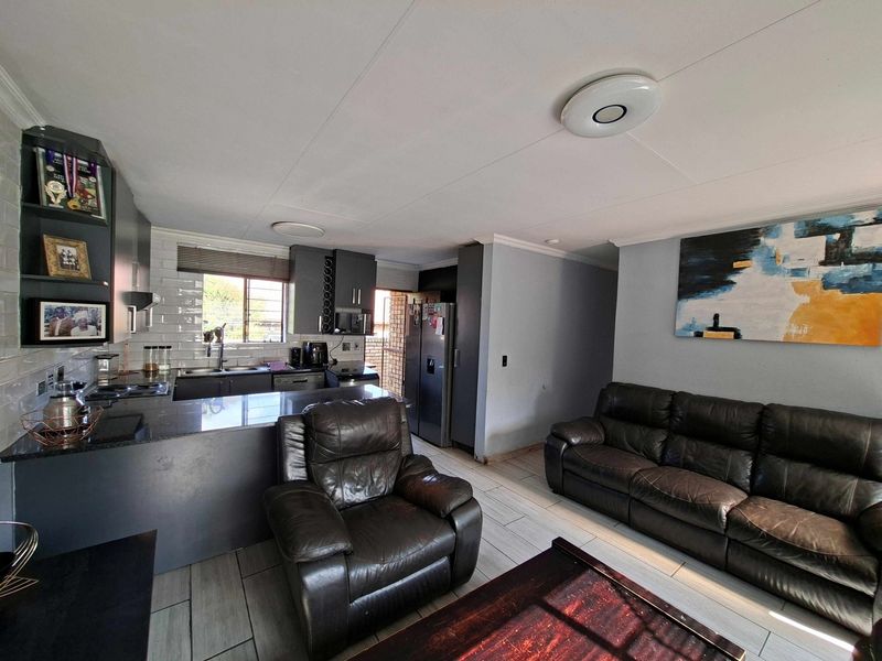 Open-plan living area featuring a modern kitchen with granite countertops, subway tile backsplash, and tiled flooring, seamlessly flowing into the lounge space.
