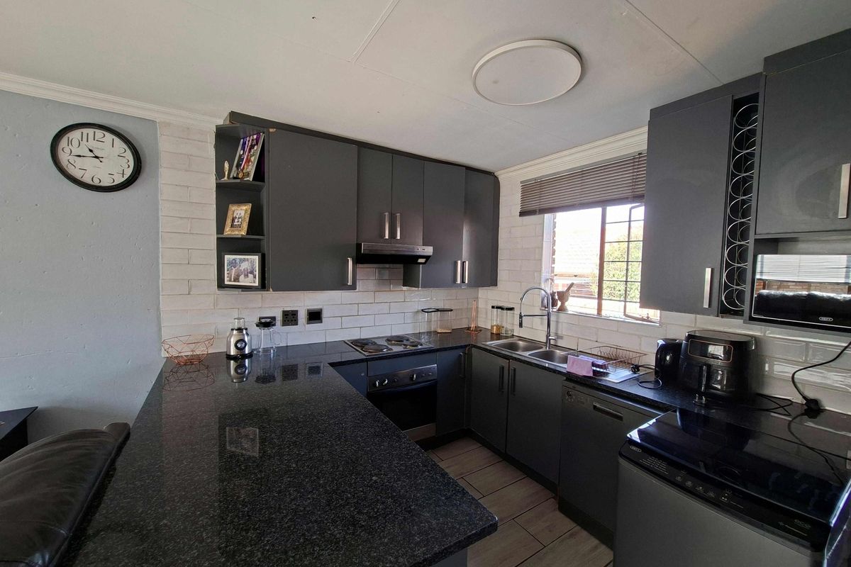 Modern kitchen featuring dark cabinetry, granite countertops, integrated appliances, and a breakfast bar, offering a functional and stylish cooking space.