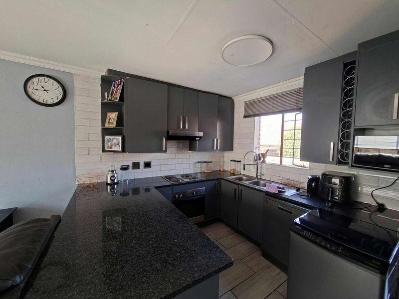 Modern kitchen featuring dark cabinetry, granite countertops, integrated appliances, and a breakfast bar, offering a functional and stylish cooking space.