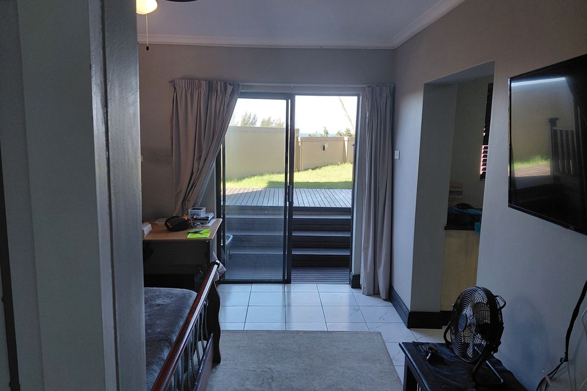 Living room featuring tiled flooring, a ceiling fan, and sliding glass doors providing direct access to an outdoor deck area.