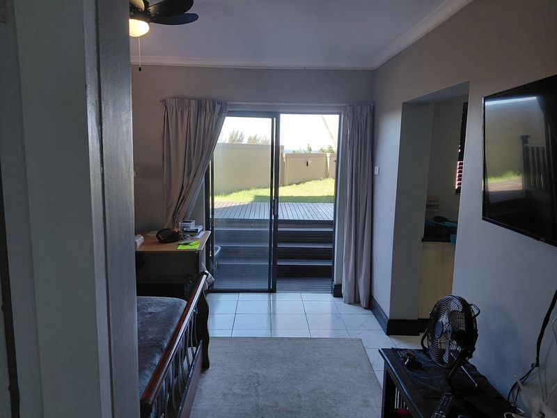 Living room featuring tiled flooring, a ceiling fan, and sliding glass doors providing direct access to an outdoor deck area.