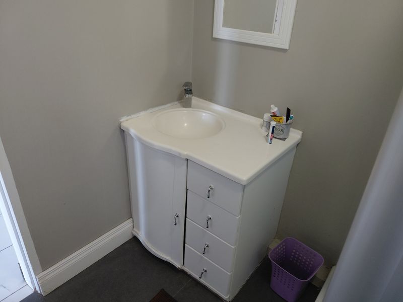 A compact bathroom vanity unit featuring a white cabinet with integrated sink, faucet, and a wall-mounted mirror.