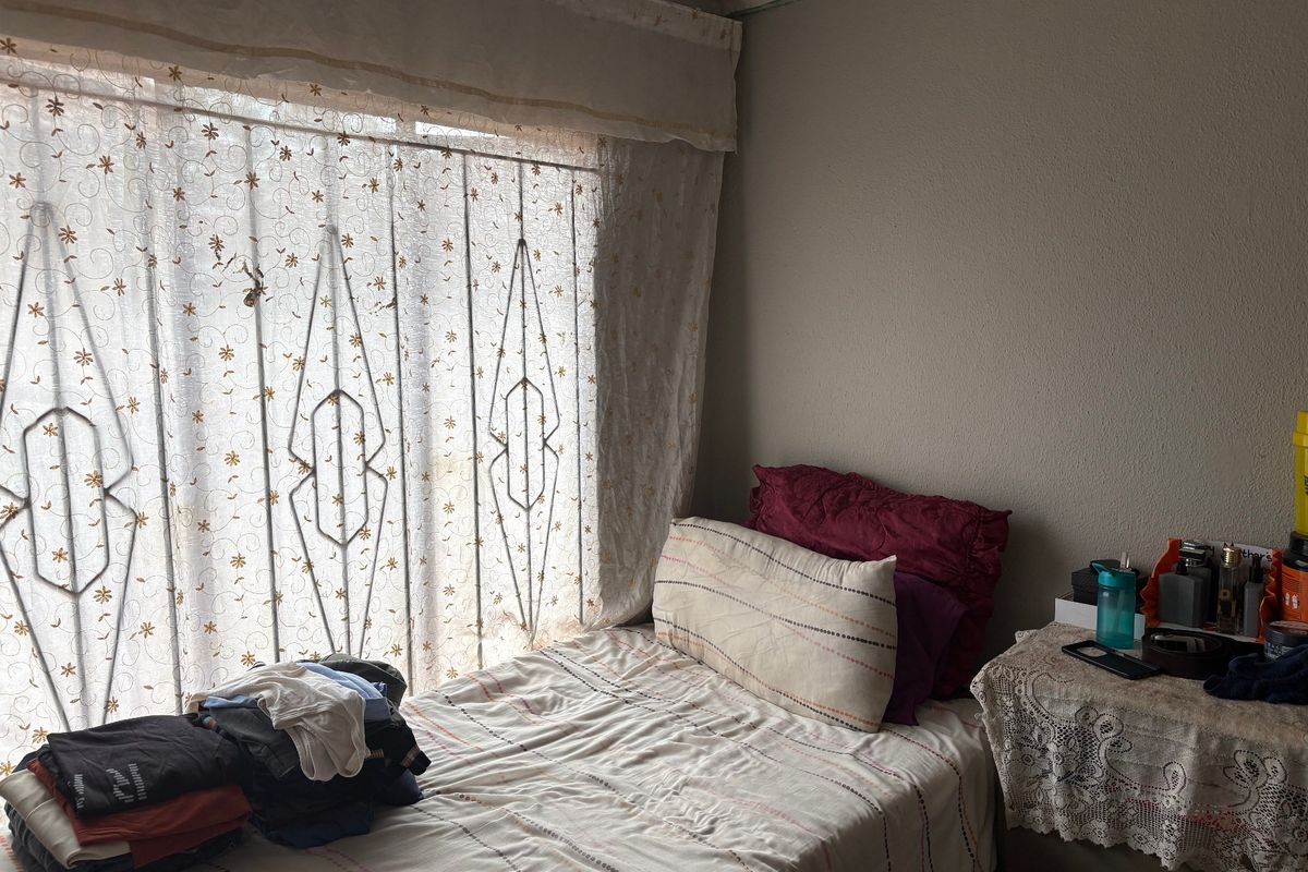 A bedroom featuring a window with a fitted security gate and curtain rail, providing natural light to the space.