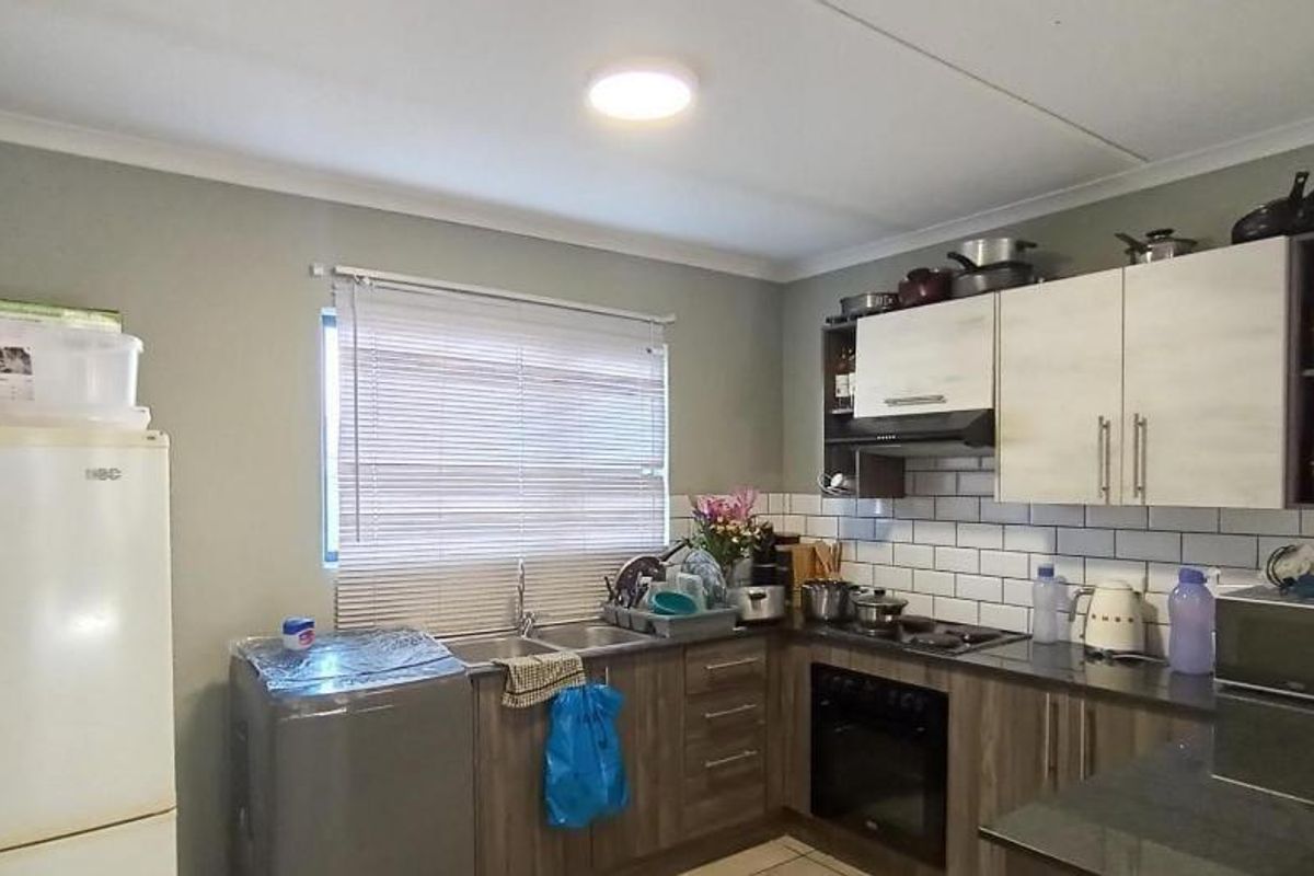 A functional kitchen featuring built-in cabinetry, a subway tile backsplash, integrated oven, hob, extractor fan, and a double sink with venetian blinds.