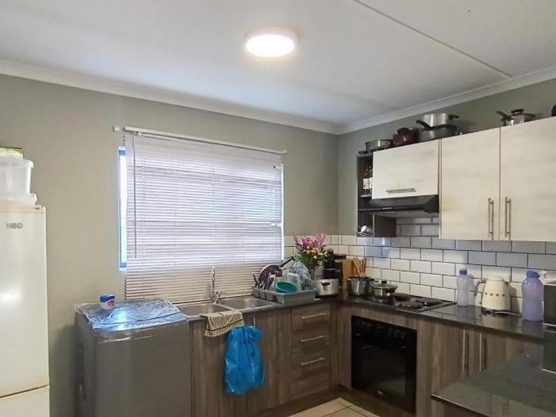 A functional kitchen featuring built-in cabinetry, a subway tile backsplash, integrated oven, hob, extractor fan, and a double sink with venetian blinds.