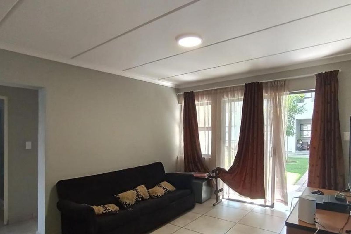 A living room featuring tiled flooring, a coved ceiling, and a sliding glass door providing access to the exterior.