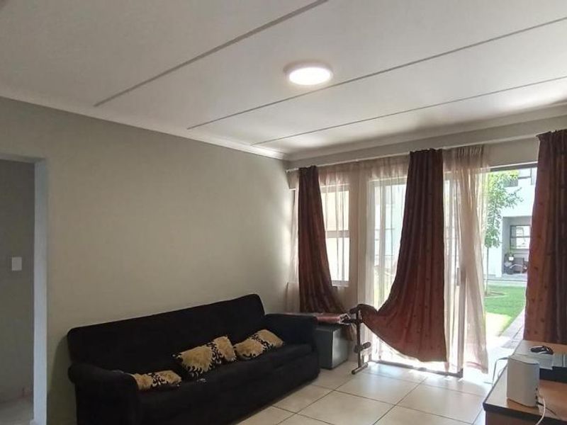 A living room featuring tiled flooring, a coved ceiling, and a sliding glass door providing access to the exterior.