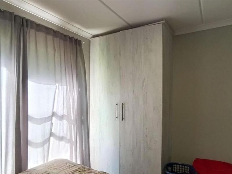 A bedroom featuring a light wood-finish built-in wardrobe and neutral wall tones, providing functional storage space.