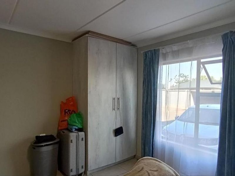 A bedroom featuring a built-in wardrobe, neutral wall finishes, and a window with natural light.