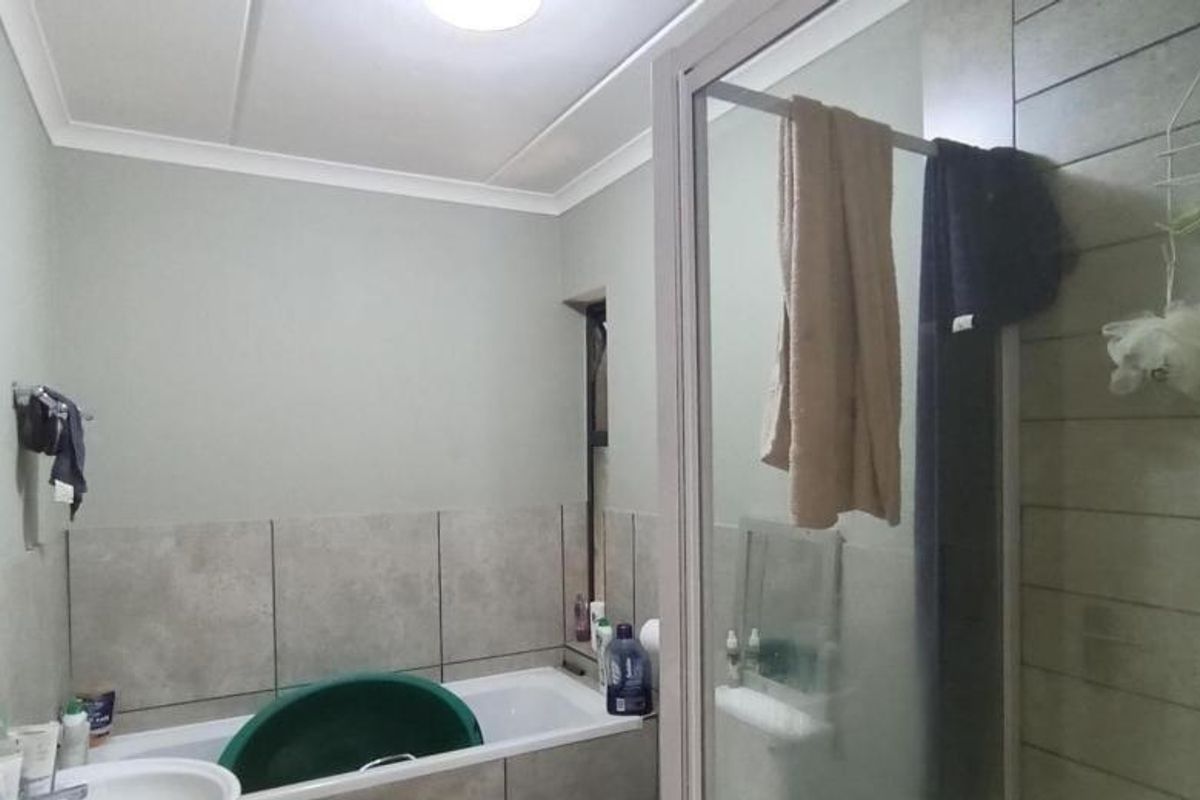 A functional bathroom featuring a bathtub and a separate shower enclosure with tiled wall finishes.