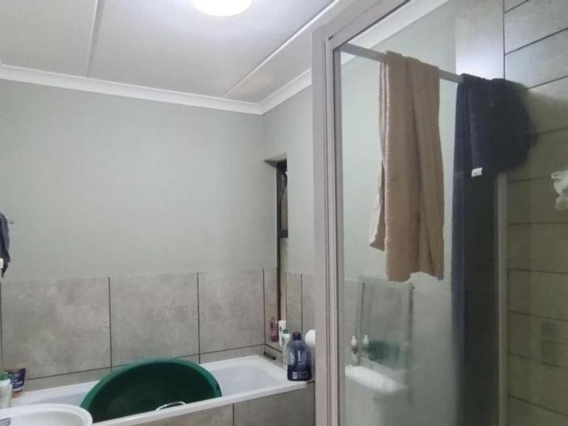 A functional bathroom featuring a bathtub and a separate shower enclosure with tiled wall finishes.
