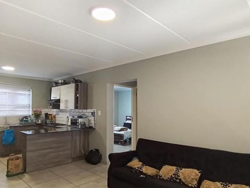 Open plan living area featuring a functional kitchen with granite countertops, cabinetry, and tiled flooring, seamlessly connected to the main living space.