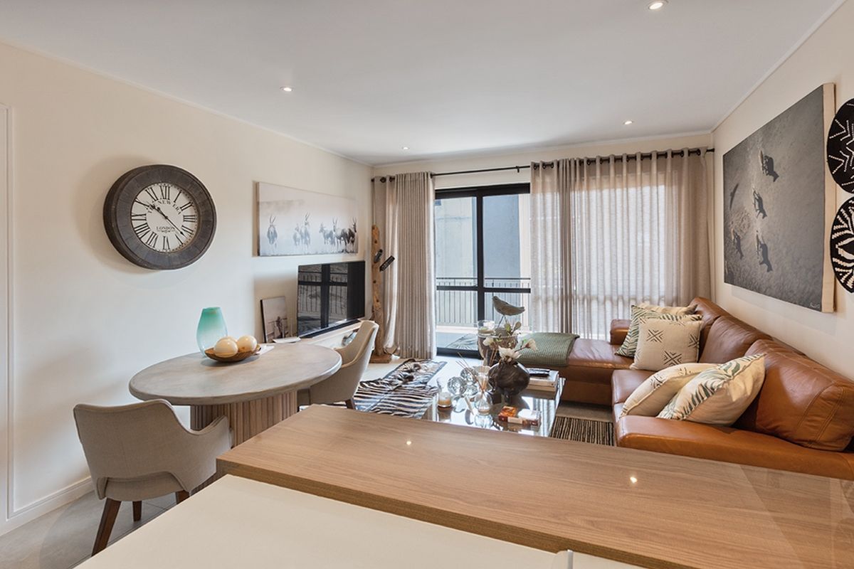 An open-plan living and dining area featuring a breakfast bar, recessed lighting, and sliding glass doors leading to a balcony.