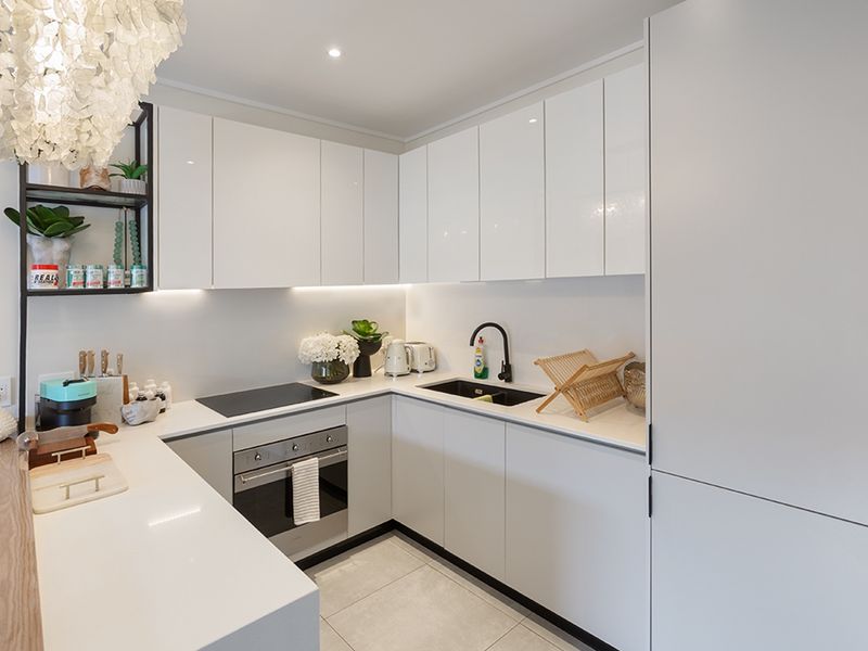Modern kitchen featuring sleek white cabinetry, quartz countertops, integrated appliances, and high-quality finishes with under-cabinet lighting.