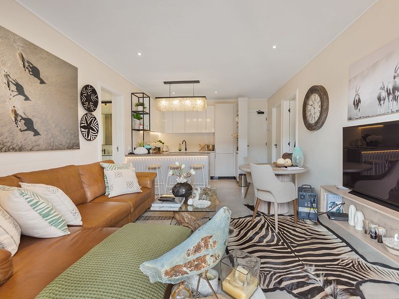 A modern open-plan living and kitchen area featuring a central island, sleek cabinetry, and recessed lighting, creating a cohesive and functional living space.