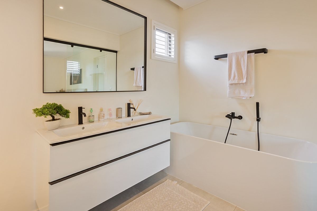 Modern bathroom featuring a sleek double vanity, freestanding bathtub, and contemporary black matte fixtures with a large wall-mounted mirror.