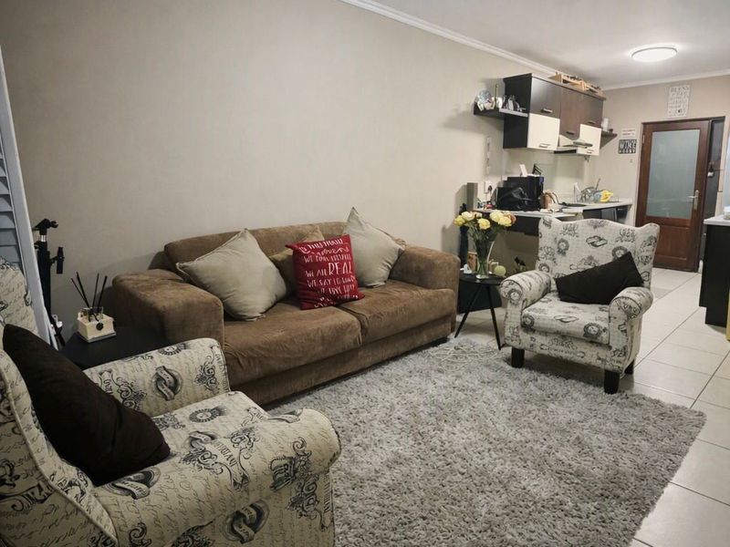Open plan living area featuring tiled flooring and a compact kitchen with built-in cabinetry and an extractor fan.