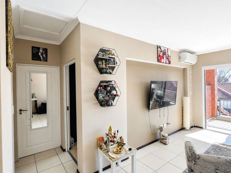 A bright living room featuring tiled flooring, a wall-mounted air conditioning unit, and a sliding glass door leading to an outdoor balcony.