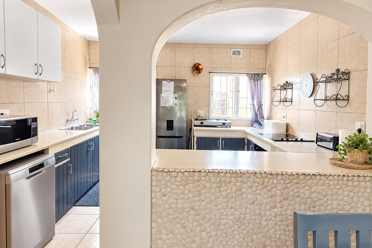 A functional kitchen featuring blue cabinetry, tiled walls, a stone-clad breakfast bar, and integrated cooking appliances, offering a practical layout for meal preparation.