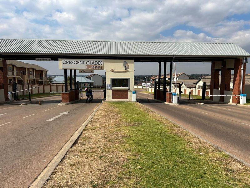 The main entrance and security gatehouse of Crescent Glades estate, featuring controlled access boom gates and brick architectural detailing.