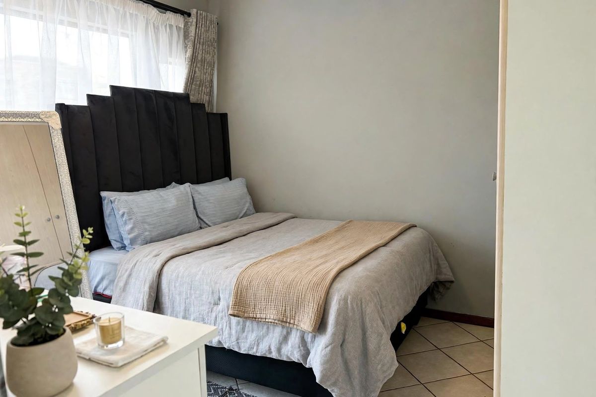 A cozy bedroom featuring tiled flooring and a window, providing a functional and comfortable living space.